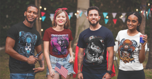 A diverse group of people wearing TeeStitch graphic t-shirts at an outdoor event. The image represents the brand's relaunch and return to order fulfillment, timed with Earth Day and centered around sustainable fashion and community.