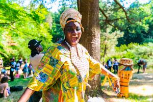 Dzidzor, a Black woman dressed in a colorful tunic and head wrap, speaking during the 2022 MassQ Ball