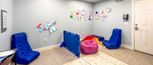 Bright, inviting playroom with colorful seating, a wall of decorative circles, and play structures for children.