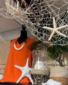 Display showing an Orange Sleeveless Top, necklace and accessories with starfish in the Long Island Summer Shop at Hicks Nurseries