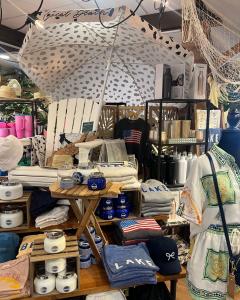 A display in the Long Island Summer Shop at Hicks Nurseries showing a chair, umbrella, folded tee shirts, candles and other accessories