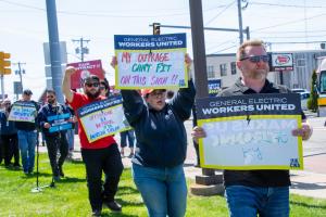 Workers holding signs protesting offshoring and other issues at GE Aerospace
