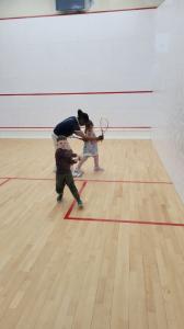 Kids gain instruction from Coach Kay Zee Sitshebo on a Squash court.