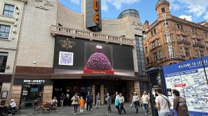 Purple preserved rose dress sculpture projected on a major Leicester Square screen above VUE Cinema.