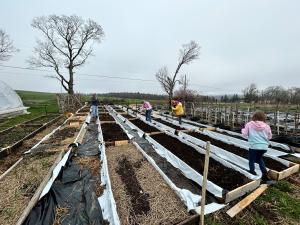 Volunteers including children and adults prepare raised garden beds for a Heart of Maine community garden.
