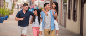 A group of young adults enjoys a leisurely stroll down a vibrant street, savoring treats and sharing smiles.