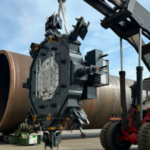 CNC Onsite's Goliath machine is seen next to a large diameter tower flange lying on its side. The machine will mill the flange after being mounted onto the flange