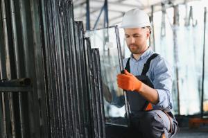  A glassmaker inspects a large glass panel for quality and clarity.