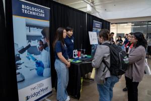bridgyear student career fair booth with two presenters discussing a Biological Technician program.