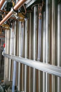 Close-up of industrial equipment featuring metallic pipes, valves, and copper fittings. The scene conveys a sense of precision and modern technology.