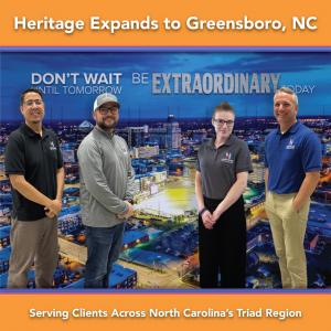 Heritage Signs & Displays team members standing in front of a wall mural that reads “Don’t wait until tomorrow. Be extraordinary today.” at the Greensboro office.