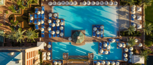 Aerial view of Renaissance Esmeralda Resort & Spa's pool area with lounge chairs, umbrellas, and palm trees, showcasing a central gazebo amidst blue water.