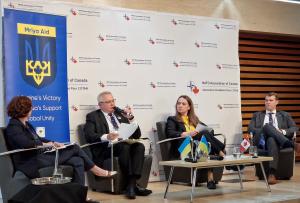 Four panelists from the "Demining Ukraine" panel discussion at the 2025 NATO Association of Canada "Safeguarding Ukraine's Future" Conference in Toronto with the NAOC and Mriya Aid banners in the background