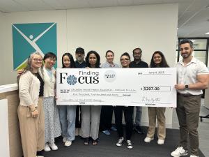 Eleven individuals from Finding Focus and the Canadian Mental Health Association – National Division pose together during a cheque ceremony in Toronto on June 4, 2025. Loretta Zambito stands to the far left and Ammar Subhan to the far right, holding an ov