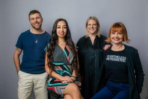 NVE Experience Agency's London leadership. From left to right: James Kyte (man in dark blue tshirt and beige slacks), Zara Mannings (woman with long dark hair in geometric print dress), Georgie Simon (woman with shoulder length blonde hair in a dark green