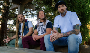 VBDC band sitting on a table outside with tress behind them (from Left to right Benji Hamlin, Seth Caro, Gary “Big G” Larason)