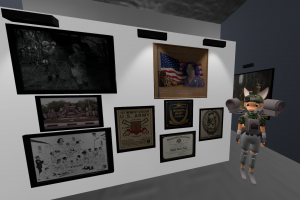 Artist in avatar with lots of camera equipment, super large camera on both shoulders standing in front of her bio exhibit inside the River Art Emporium which is a dedication to Women Army Corps. The gallery is for all veteran's art is nestled in the Ferry