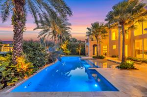 Twilight photo of a luxury backyard with glowing blue pool lights, tropical landscaping, and elegant outdoor design in Harbor Beach.