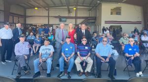 Rick Mantei, Lisa Mantei, And Joe Wilson standing next to the surviving veterans in attendance