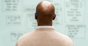 Man looking at a whiteboard from behind