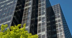Outdoor view of glass tower office building with trees.