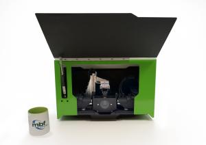 SLICE™ Light Sheet Microscope by MBF Bioscience shown with open lid, revealing internal imaging components. Compact green benchtop 3D microscope placed next to MBF-branded mug for size reference.