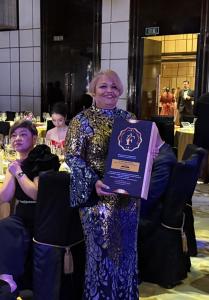 Dr. Vicki Wright Hamilton standing in a formal ballroom, smiling and holding her FLUXX Awards plaque after receiving the Business Growth Strategist Woman of the Year – Consulting (USA) honor at the 2025 ceremony in Hong Kong.