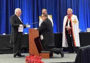 Michael Fomkin kneels during his knighthood ceremony as a sword is placed on his shoulder by His Royal Highness Don Rafael Andujar y Vilches, Prince Grand Master of the Royal Order of Contantine the Great and Saint Helen