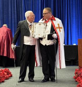 Sir Michael Fomkin stands beside Prince Rafael Andujar y Vilches of the Royal Order, proudly holding his official knighthood certificate. Both wear ceremonial regalia representing the chivalric traditions of the Royal Order, which honors global leaders fo