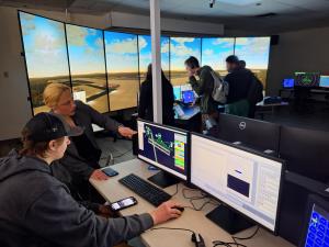 An image of Amy Parish, Vice President of North America Programs for UFA, Inc., guiding Cameron Robson, SUNY Schenectady Aviation Science major, on the new Air Traffic Control simulator at SUNY Schenectady.