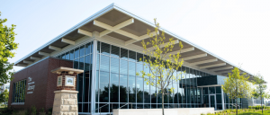 Modern library building with large glass windows, surrounded by greenery, featuring a prominent sign reading "The Indianapolis Public Library."