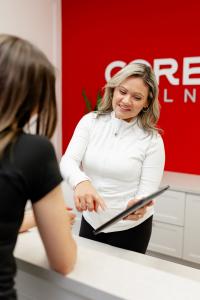 CoreLife Wellness team member at front desk reviewing a treatment plan with a client, supporting pelvic floor therapy and core health in Oakville.