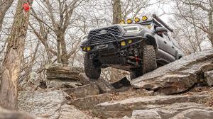 Toyota Tacoma equipped with Ride Shocks suspension navigating rocky off-road trail during overlanding adventure.