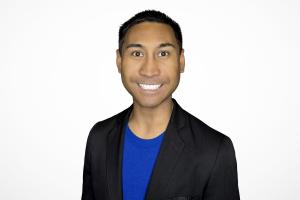 Jessper Maquindang, team-building and leadership consultant, smiling in a professional headshot. He is wearing a black blazer over a blue shirt on a white background.