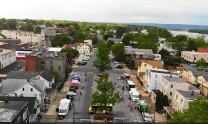 Aerial view of downtown New Cumberland, PA during a local Food Truck Rally. Colorful trucks and community members line the closed-off street between shops and historic homes, with the Susquehanna River visible in the background.