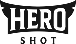 HERO SHOT Photography logo: bold black word ‘HERO’ in a curved banner style above the spaced serif word ‘SHOT’ on a white background.