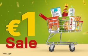Green background featuring bold yellow “€1” and red “Sale” text next to a metal shopping cart filled with various packaged Indian grocery items.