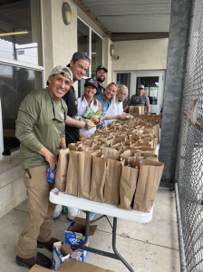 A group of Hilliard Law employees stand around a table full of sack dinners to distribute.