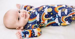 Baby wearing a dark blue bamboo zipper pajama with rainbows, clouds, and rain