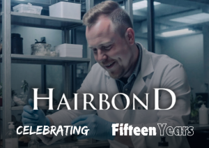 Scott Michaels, founder of Hairbond, smiling while working in a lab wearing a white coat and blue gloves. The Hairbond logo is overlaid along with the text "Celebrating Fifteen Years."