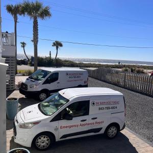 Two 911 Service Today appliance repair vans parked outside a beachfront home under palm trees, promoting emergency appliance repair services in coastal South Carolina.