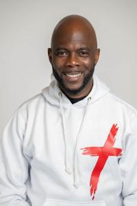 Man with white sweat shirt with red cross on the front