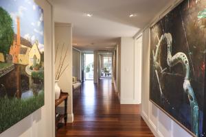 Interior hallway with timber floors, bench seating, and large artwork, showing natural light and soft detail in a Quiet Luxury Brisbane home.