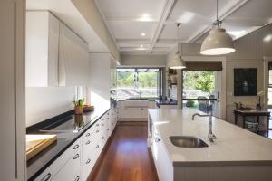 Bright kitchen with white cabinetry, timber flooring, pendant lighting, and outdoor views, designed by Dion Seminara Architecture in Brisbane.