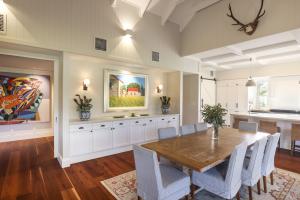 Dining area with timber floors, white cabinetry, vaulted ceiling, and framed artwork, designed by dion seminara architecture in Gregor's Creek..