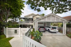 Renovated Queenslander home in Hawthorne with white picket fence, timber detailing, and new carport, designed by Dion Seminara Architecture.