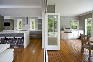 Open-plan kitchen and covered outdoor area with timber flooring, modern cabinetry, stainless steel appliances, and bifold doors, designed by Dion Seminara Architecture.
