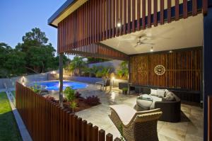 Outdoor entertaining area with timber screen, ceiling fan, lounge seating, and pool, part of a Camp Hill renovation by Dion Seminara Architecture.