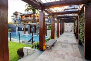 Outdoor area of Auchenflower home with pool, timber pergola walkway, glass fencing, and landscaped garden, designed by Dion Seminara Architecture.