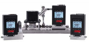 A mass flow controller on the left, a pump controller Coriolis meter in the center and a CODA Coriolis mass flow meter on the right. All the instruments have lit LCD operational displays, black casings, red CODA logos and steel flow bodies at the base.